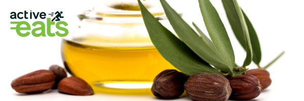 Image showing jojoba tree leaves with their fruits and jojoba oil adjacent to it in a glass bowl