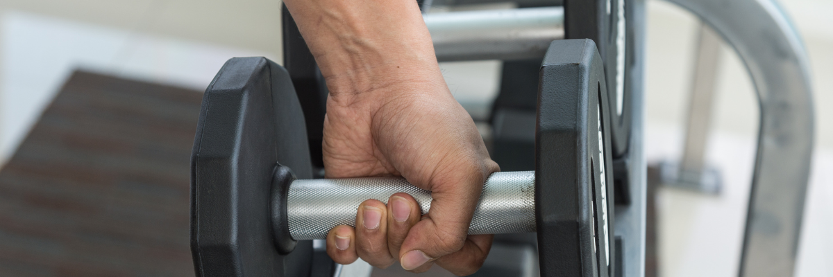 image showing a hand about to lift a heavy weight dumbbell.