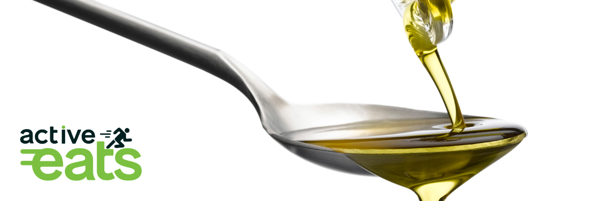 image shows one teaspoon of olive oil poured from a glass bottle.