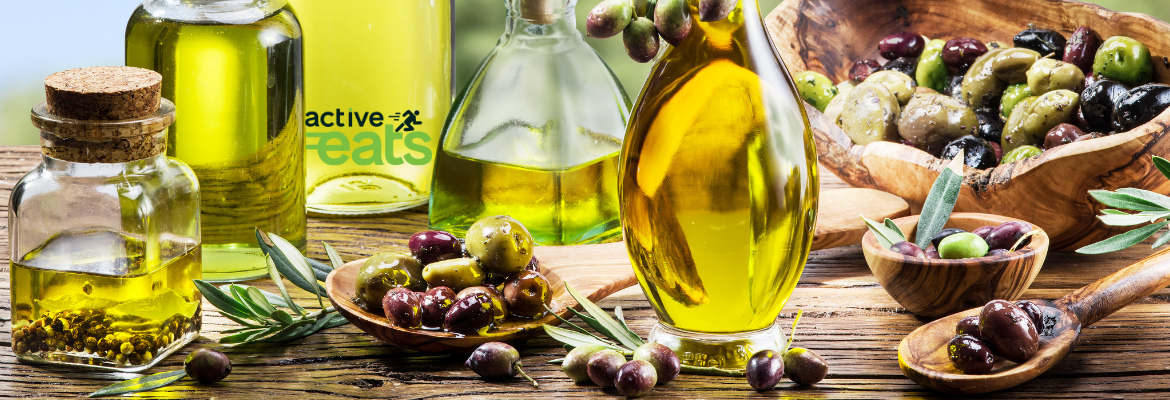 Image shows glass bottles containing olive oil and olives around them.